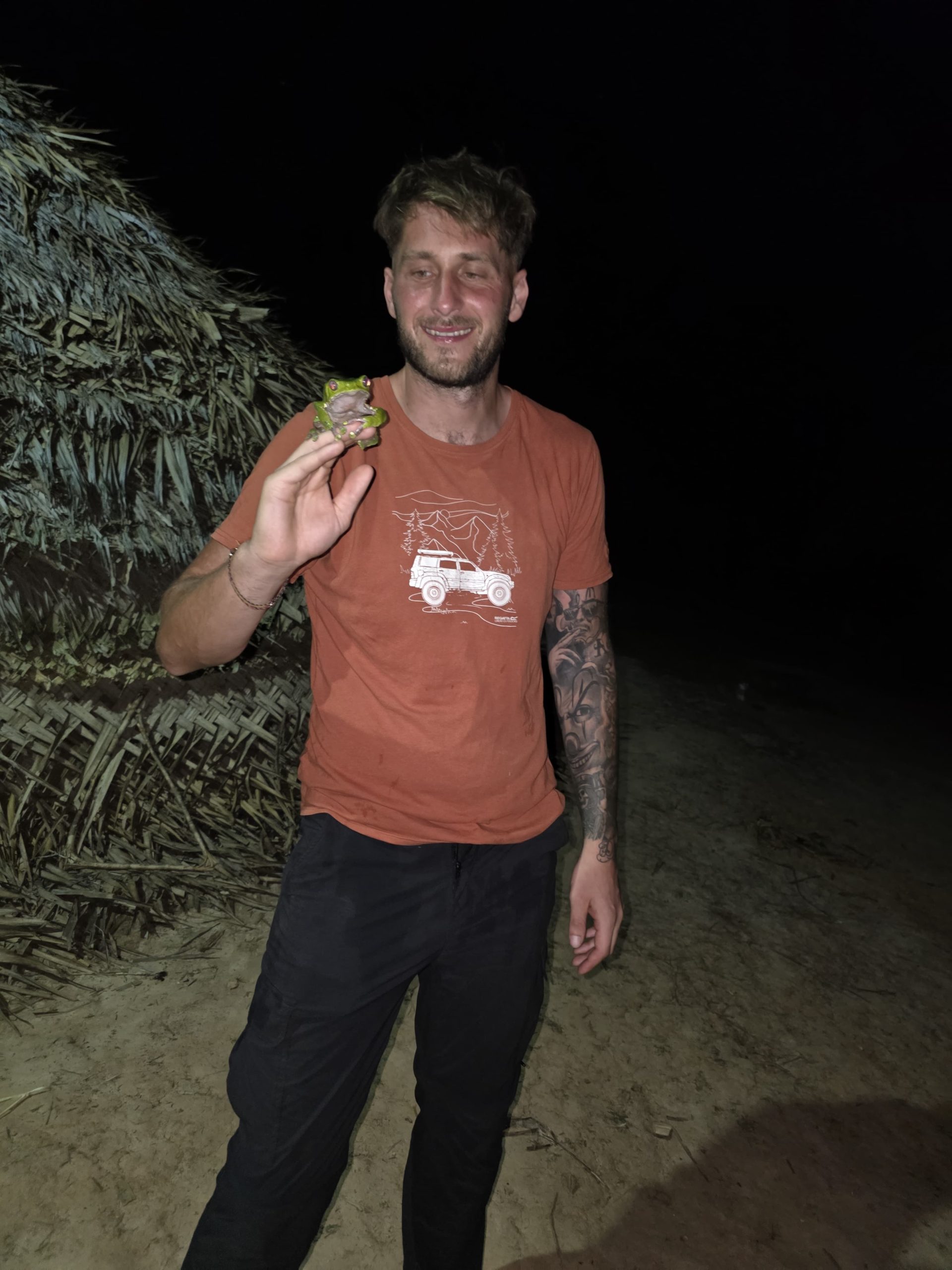 Warriors Wellbeing practitioner holding a frog outdoors at night in the Amazon